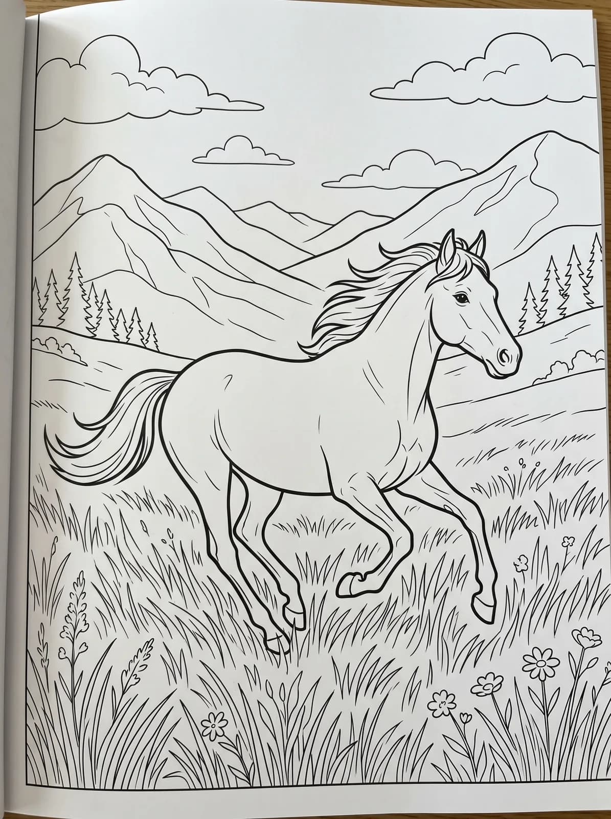 Black-and-white storybook colouring page: A horse galloping through a field of long grass with mountains behind